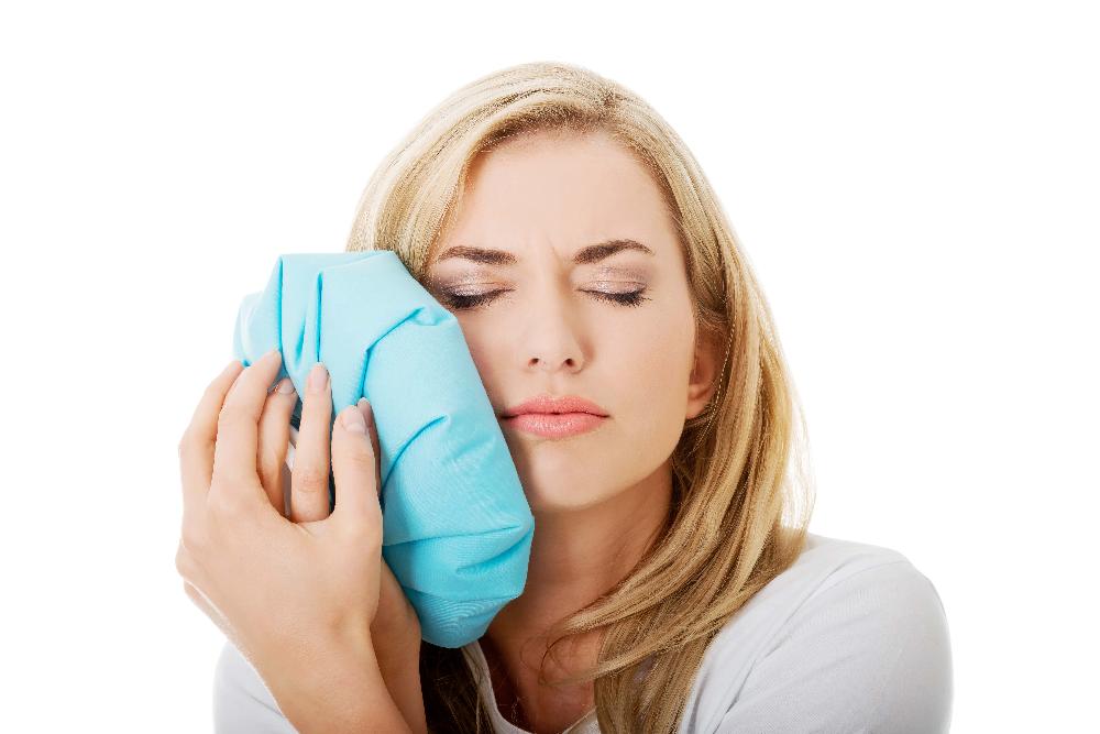 woman cold compressing her right cheek