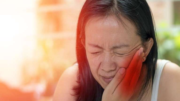 woman holding her left cheek while in pain